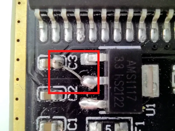 Close-up near capacitor C3 and the AMS1117-3.3 regulator, with a soldered bridge wire highlighted